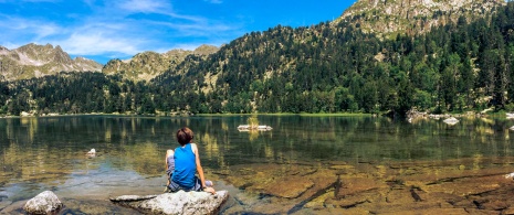 Child sitting by a lake in the Aigüestortes i Estany de Sant Maurici National Park, Catalonia Child sitting by a lake in the Aigüestortes i Estany de Sant Maurici National Park, Catalonia