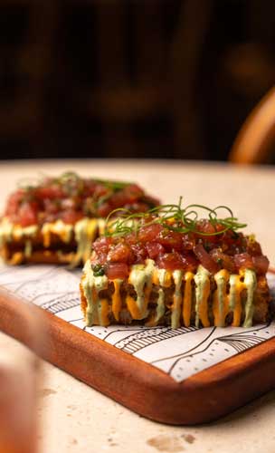 Tostada de camarão com mexilhão, crudo de atum, pil-pil de chorizo e crema de jalapeño - Manioca JK