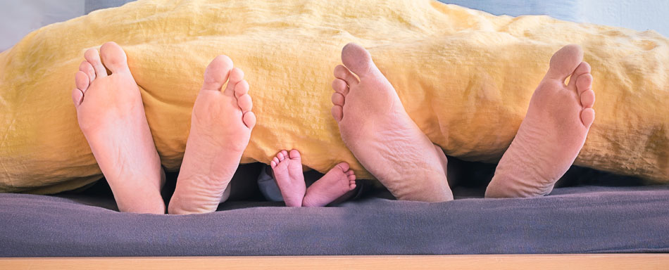 Feet of a family sticking out of a bed Feet of a family sticking out of a bed