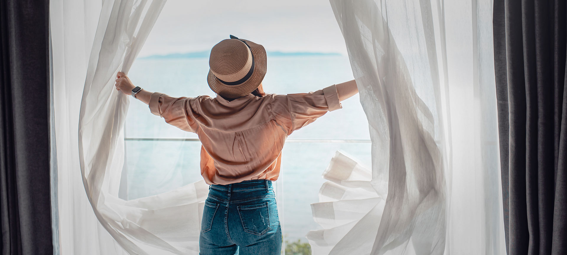 A tourist opening the curtains to their room