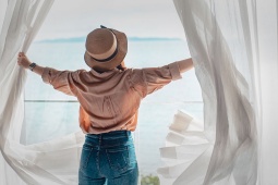 Touristin öffnet die Vorhänge ihrer Unterkunft