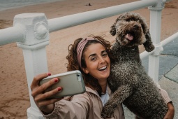 Turista che scatta un selfie con il proprio animale domestico in una spiaggia di Gijón, Asturie