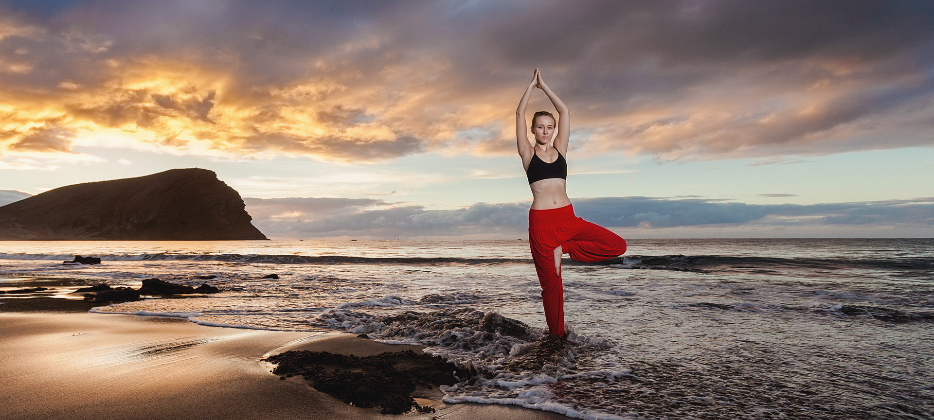 Girl doing yoga at sunset on La Tejita de Granadilla de Abona beach in Tenerife, Canary Islands