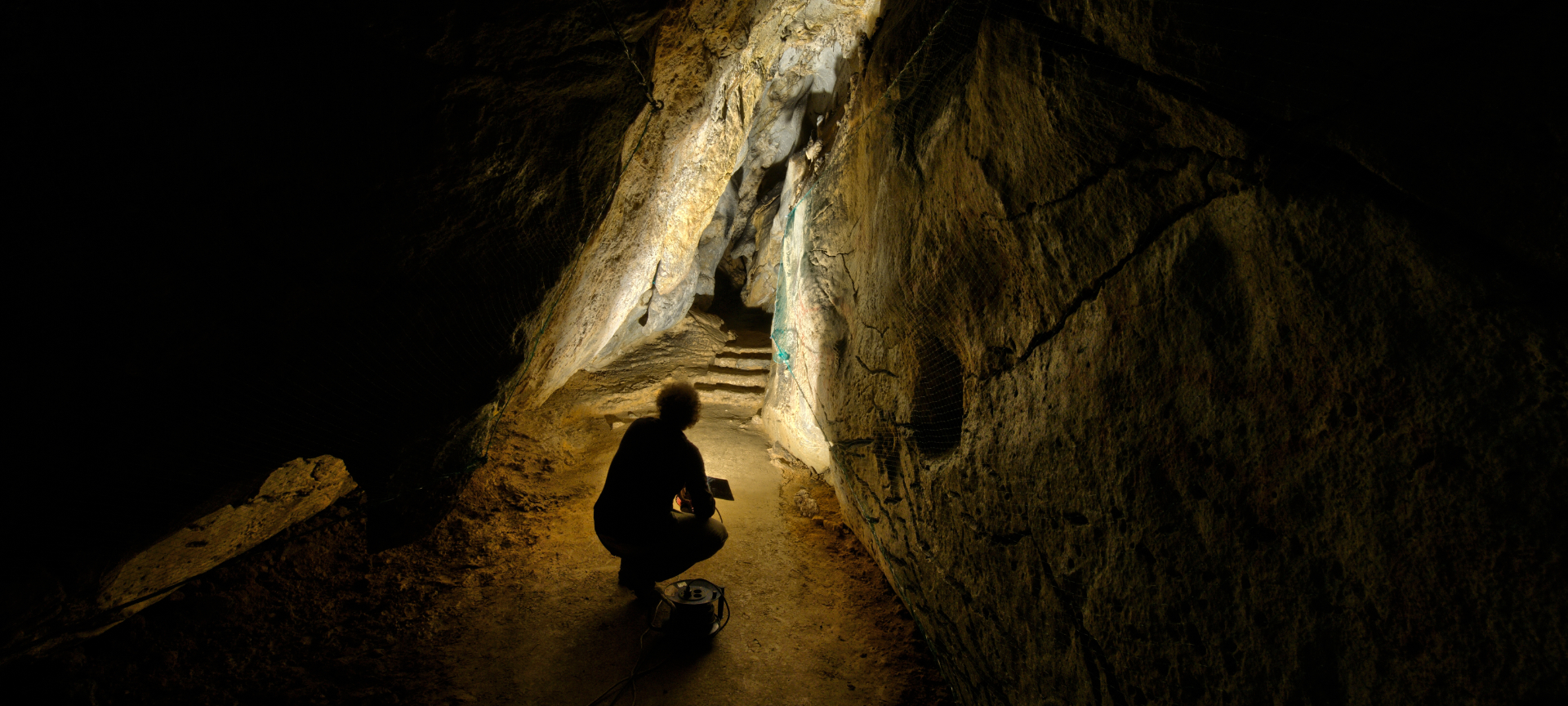 Man illuminating rock art representations in the Chufín Cave in Riclones, Cantabria
