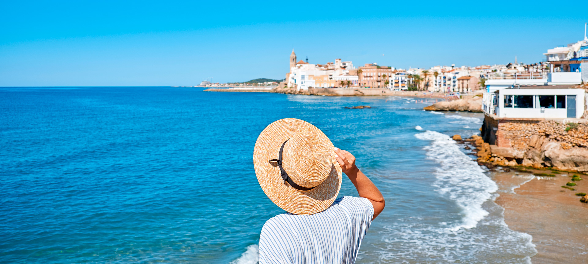 Frau, die das Meer und die Kirche Sant Bartomeu in Sitges betrachtet