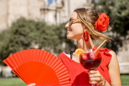 扇子とサングリアを持った赤い服の女性