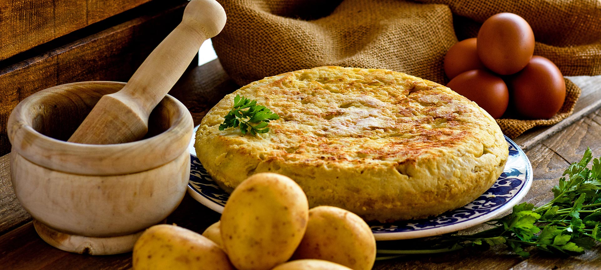 Spanish omelette with products to make it and a mortar