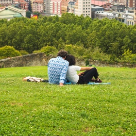 Couple watching a beautiful panoramic view of Bilbao sitting in the park on the hill above the Old Town