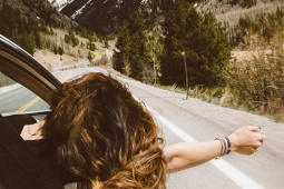 Menina olha pela janela de um carro em uma estrada nas montanhas