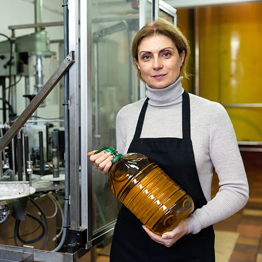 Woman holding up a bottle of olive oil in a factory