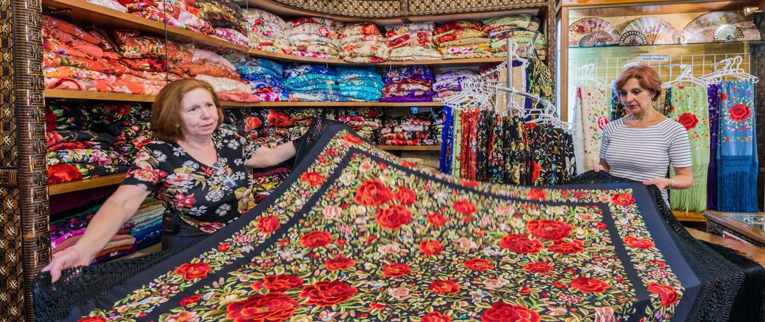 Eine Frau beim Kauf eines Manilatuches in einem Laden in Sevilla Eine Frau beim Kauf eines Manilatuches in einem Laden in Sevilla