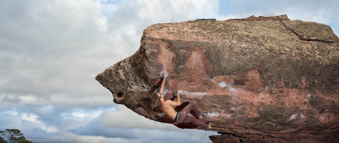 Mann klettert auf einen Felsblock in der Sierra de Albarracín in Teruel, Aragón, Spanien.