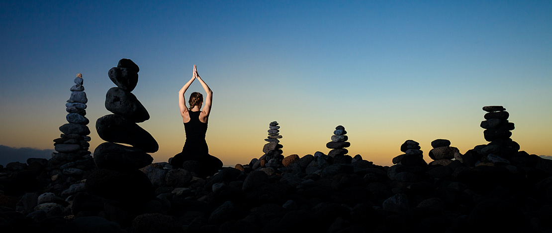 Woman doing yoga at sunset on Duque de Adeje beach in Tenerife, Canary Islands