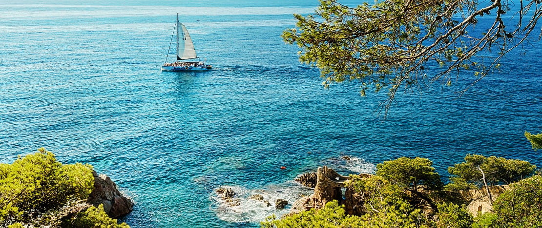 Sailboat sailing on the coast of Lloret de Mar in Girona, Catalonia Sailboat sailing on the coast of Lloret de Mar in Girona, Catalonia