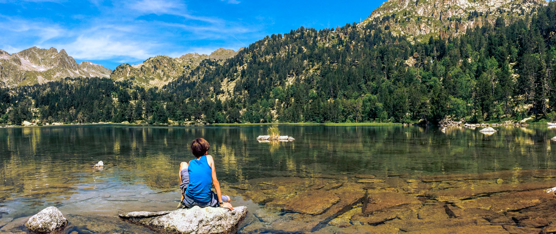 Dziecko siedzące nad jednym z jezior Parku Narodowego Aigüestortes i Estany de Sant Maurici w Lérida, Katalonia